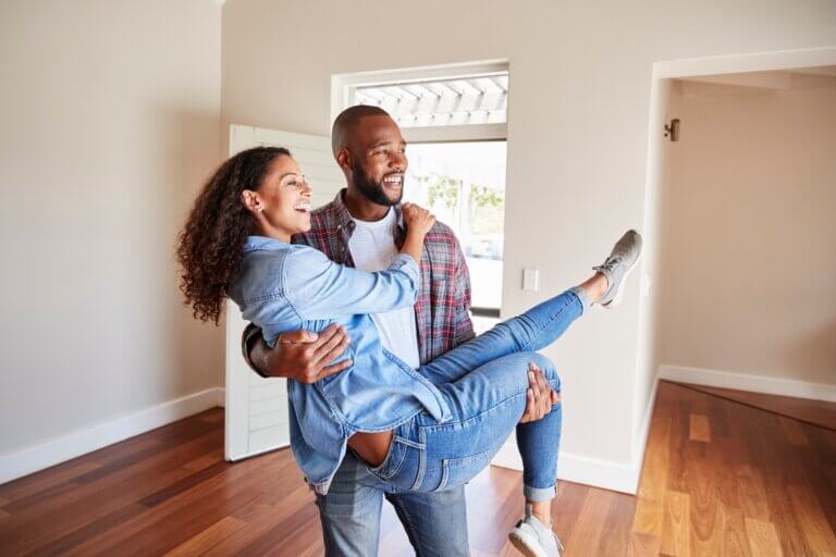 A happy couple walk into the home they financed with a flexible credit union home loan.