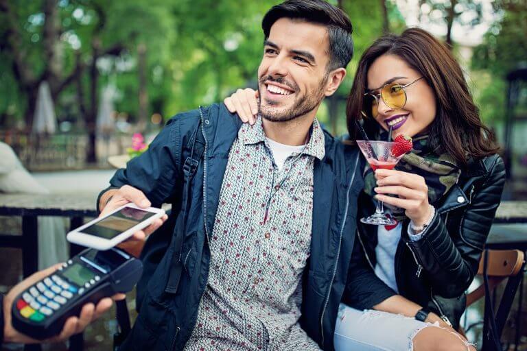 Man is paying with his mobile phone in the bar