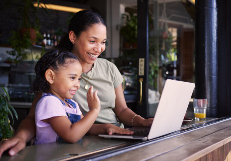 A mom sitting with her young daughter in a Portland coffee shop while opening a kid's checking account on a laptop.