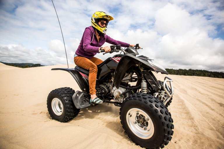 A female riding an ATV through the sand dunes in Oregon.