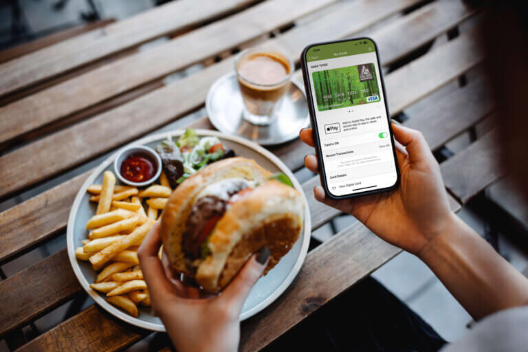Person using the Columbia Credit Union Card Manager app on a smartphone at a restaurant